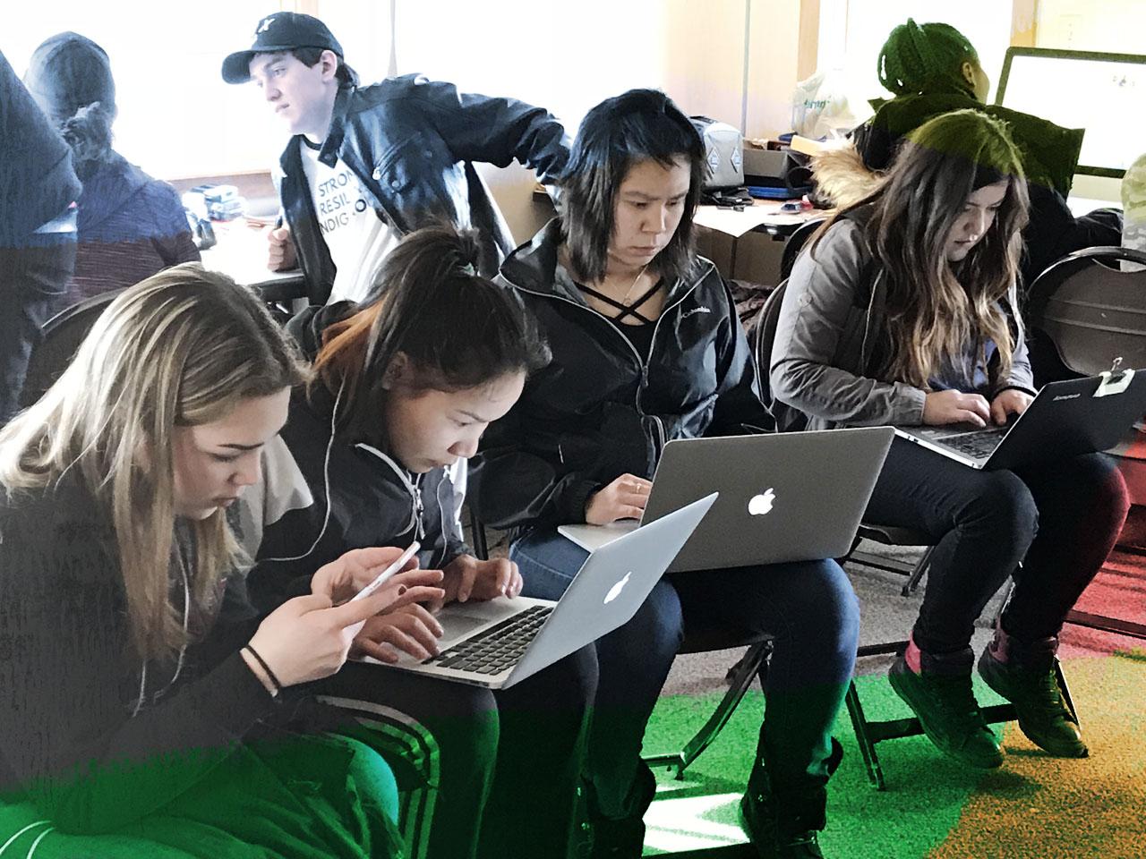 Un groupe de jeunes assis avec des portables remplissant les sondages en ligne Partageons nos histoires.